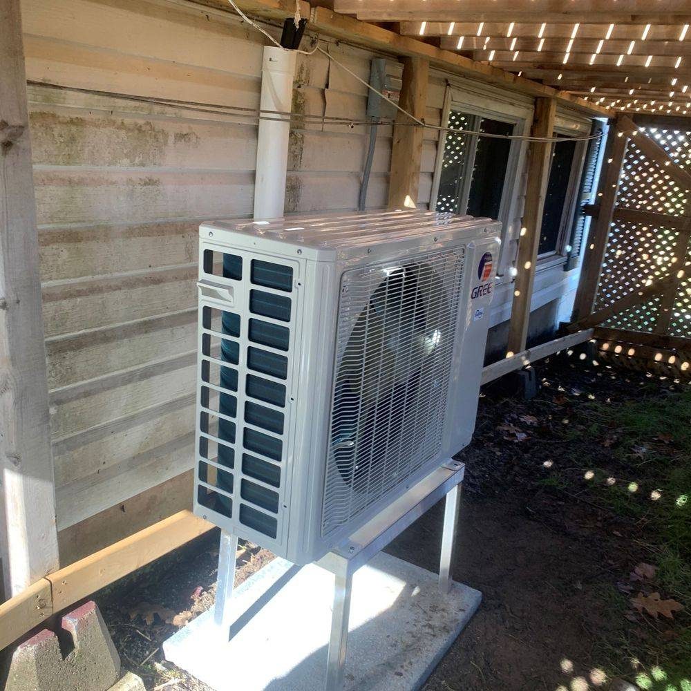 Gree outdoor heat pump unit on a stand under a deck with white lattice